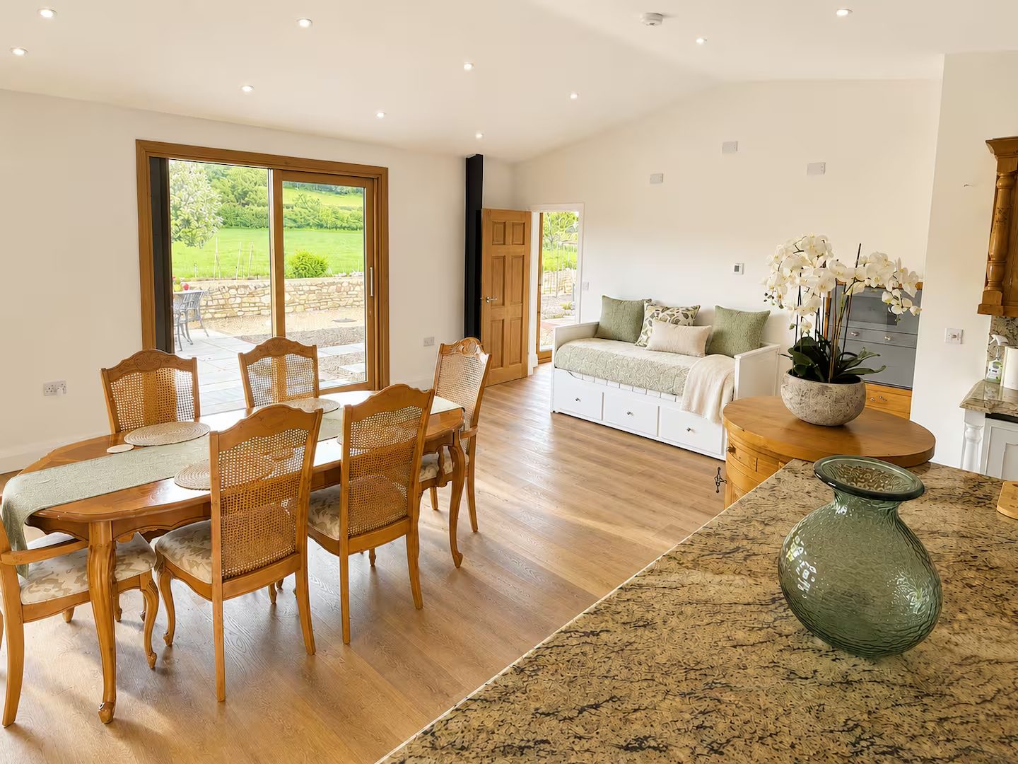 Open-plan dining and day bed with doors onto the countryside